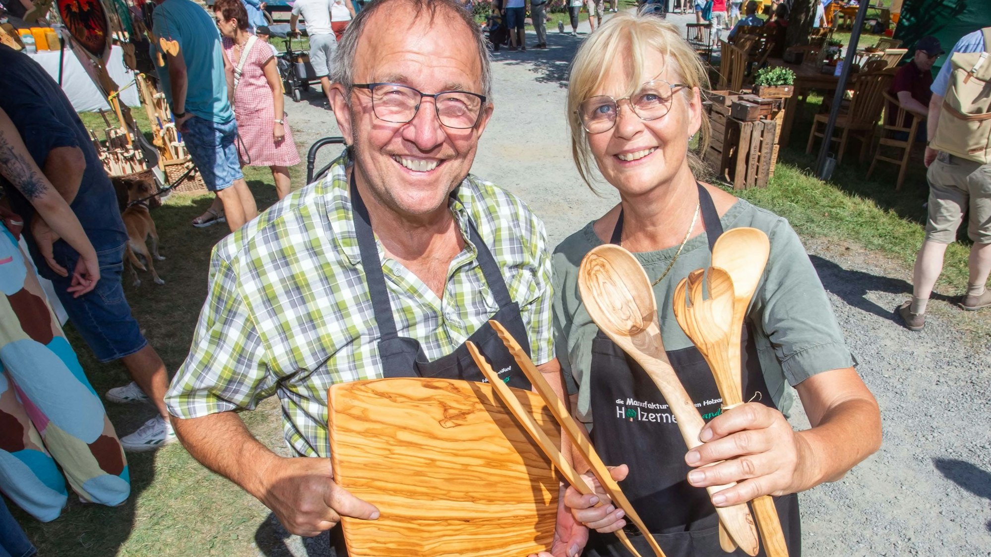 Ein Mann und eine Frau präsentieren Küchenbesteck aus Holz auf einem Markt.