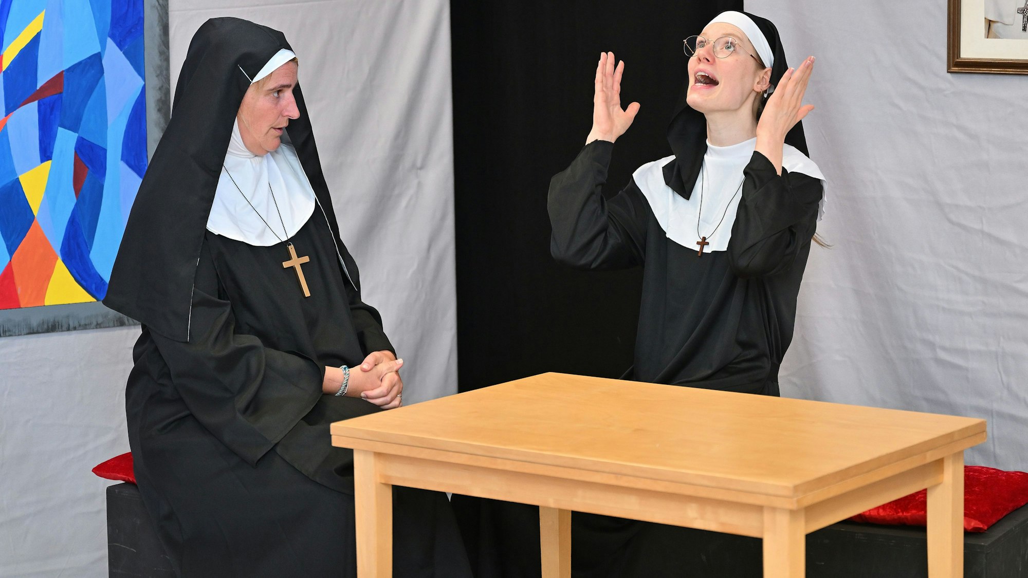 Zwei Schauspielerinnen in Nonnenkostümen machen ratlose Gesten.