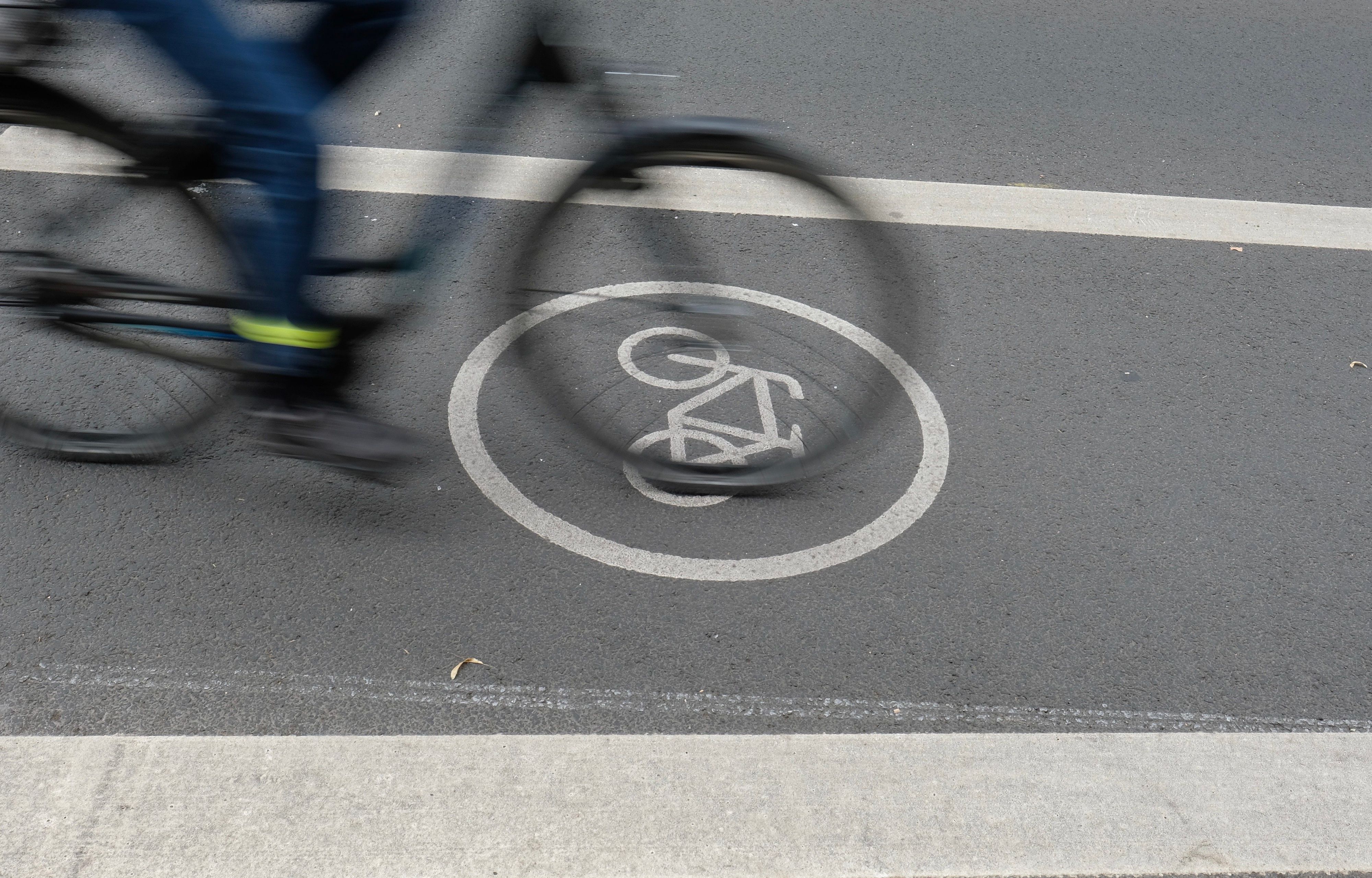 Ein Fahrradfahrer fährt auf dem Radfahrstreifen einer Fahrbahn. Ein Fahrradweg-Piktogramm ist auf der Fahrbahn in Weiß angebracht.