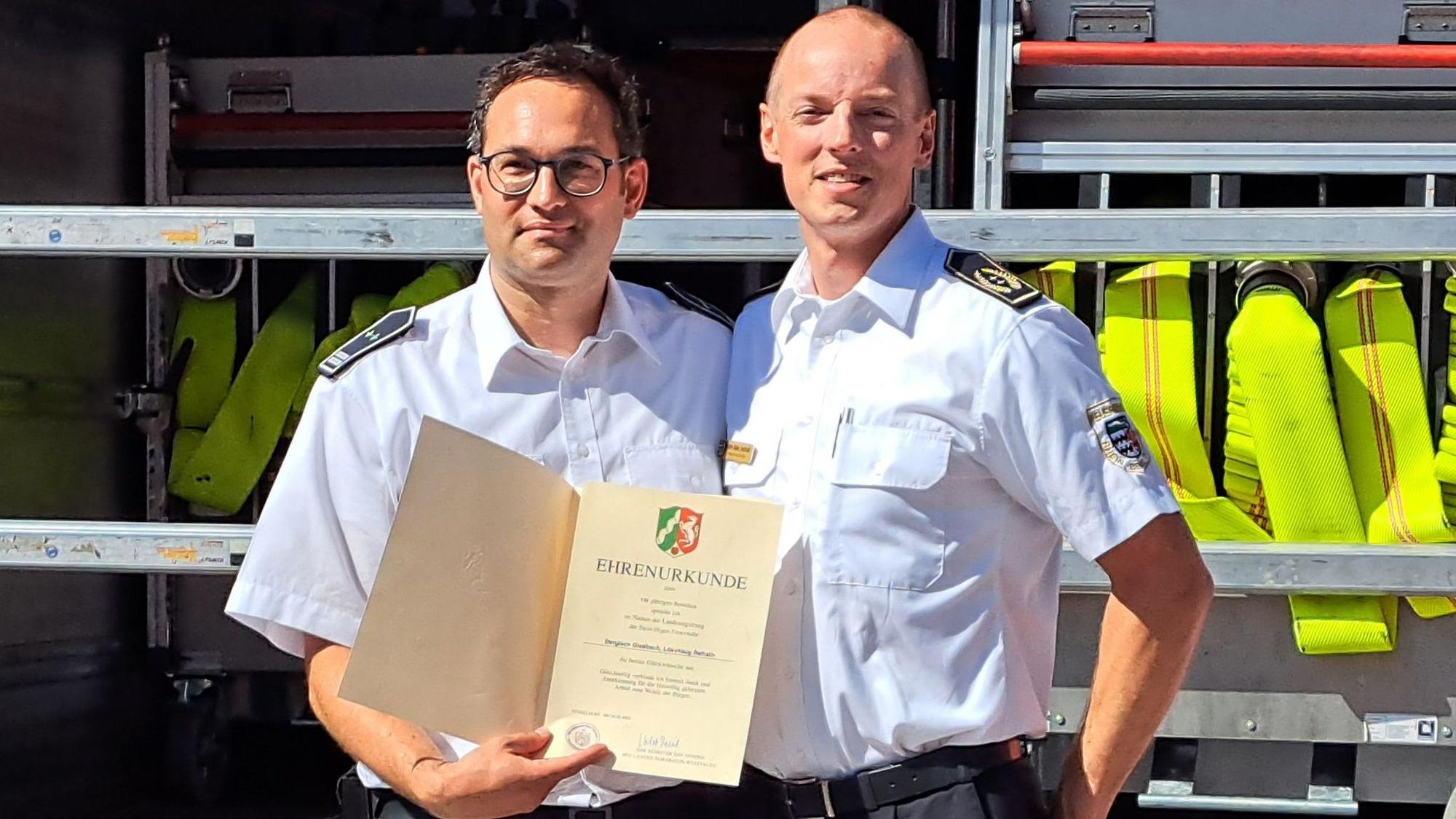 Kreisbrandmeister Martin Müller-Saidowski (r.) hat Löschzugführer Felix Vorndran zum 125-Jährigen der Einheit eine Urkunde von Innenminister Herbert Reul übergeben.
