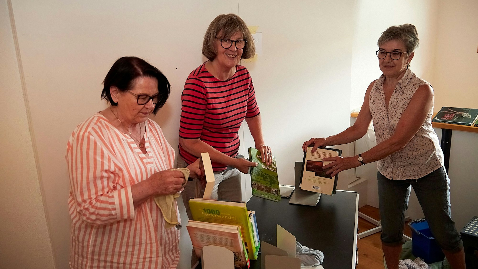 Die drei Frauen stauben Bücher ab.