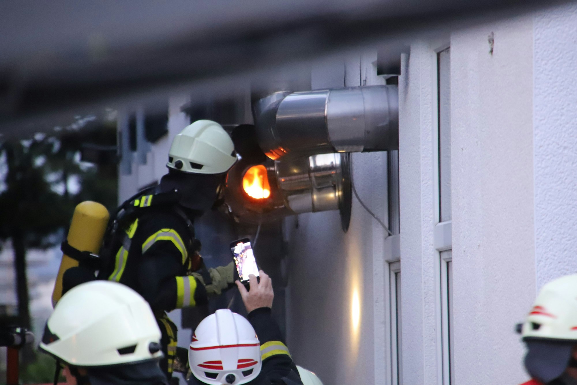 Ein Feuerwehrmann beobachtet die Flammen in einer Revisionsöffnung eines Abzugsrohres.