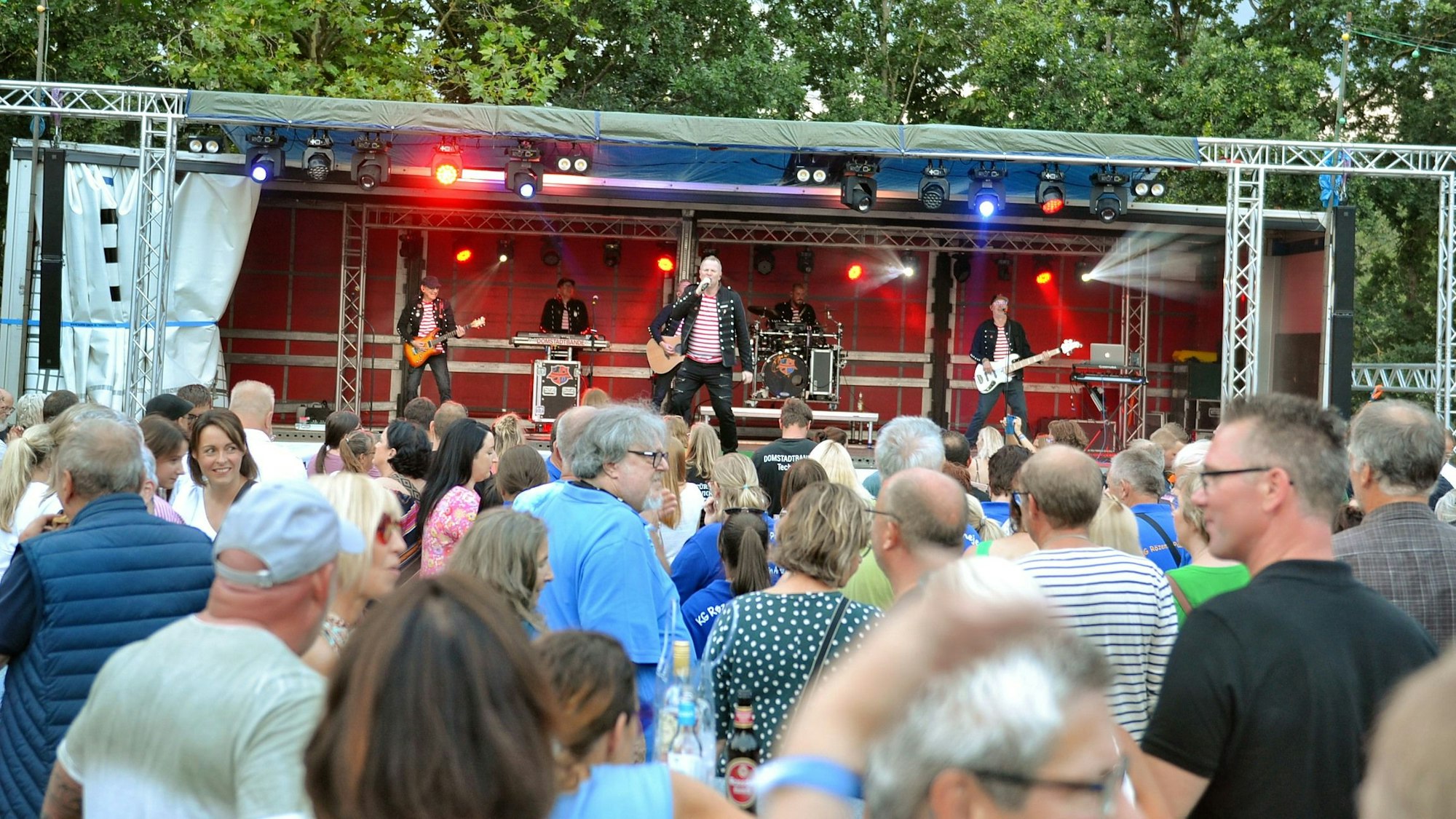 Eine Band spielt auf einer Bühne vor Publikum im Freien.