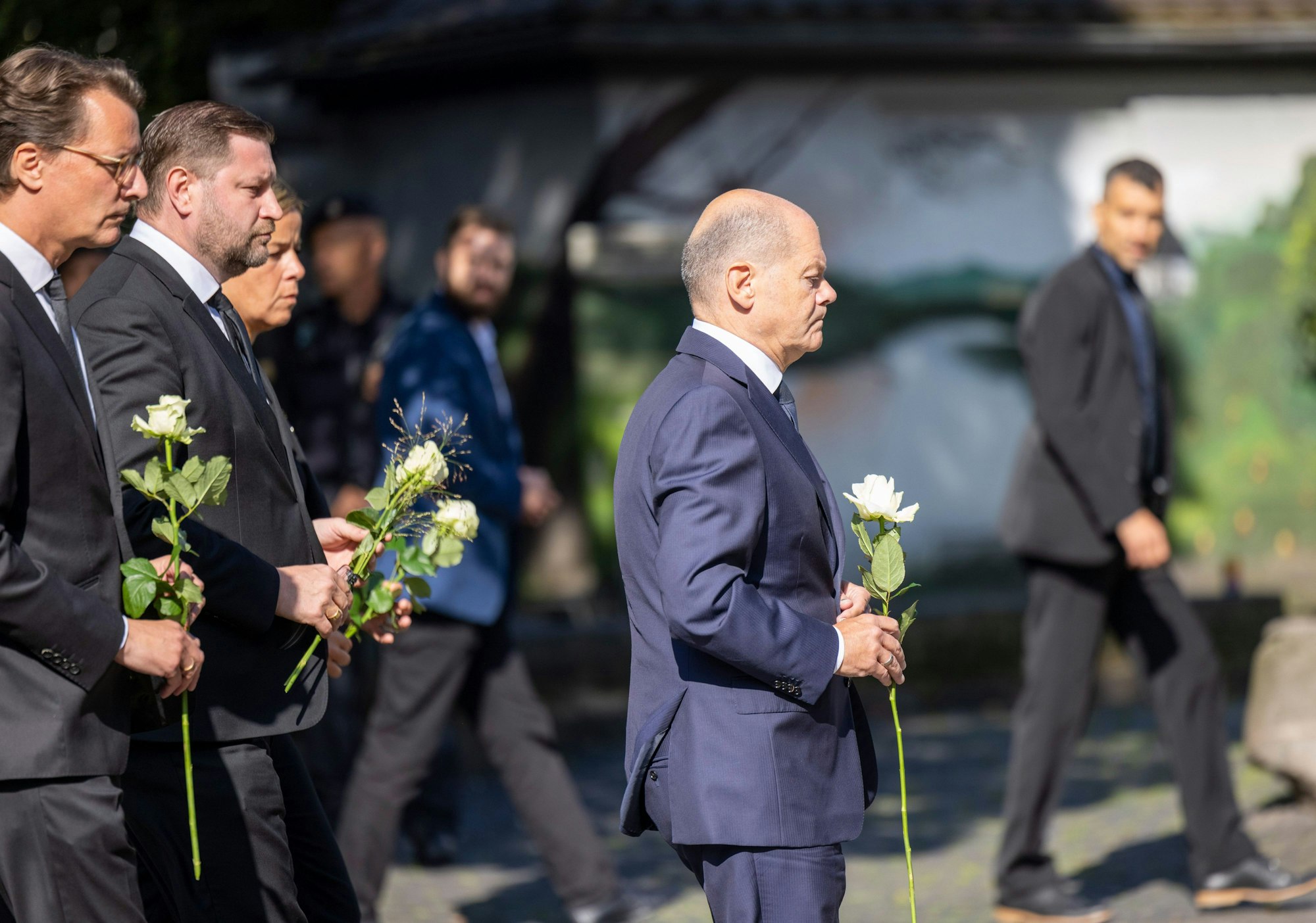 Hendrik Wüst (l-r, CDU), Ministerpräsident von Nordrhein-Westfalen, Tim Kurzbach (SPD), Bürgermeister von Solingen, Mona Neubaur (Grüne), stellvertretende Ministerpräsidentin von Nordrhein-Westfalen, und Bundeskanzler Olaf Scholz (SPD) legen Blumen an einer Kirche in der Nähe des Tatorts ab.