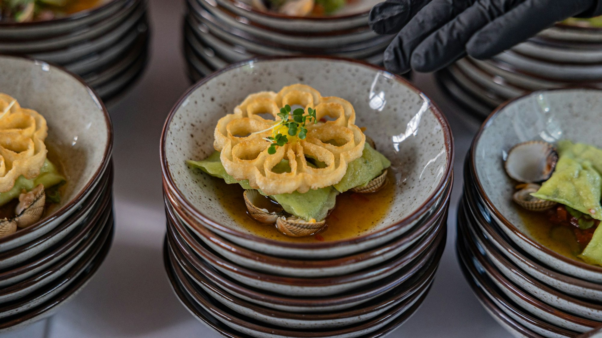 Die Sylter Muschel-Teigtasche mit Safran und Champagner verfeinert, präsentiert von Küchenchef Sönke Höltgen und seinem Team von KölnSky.