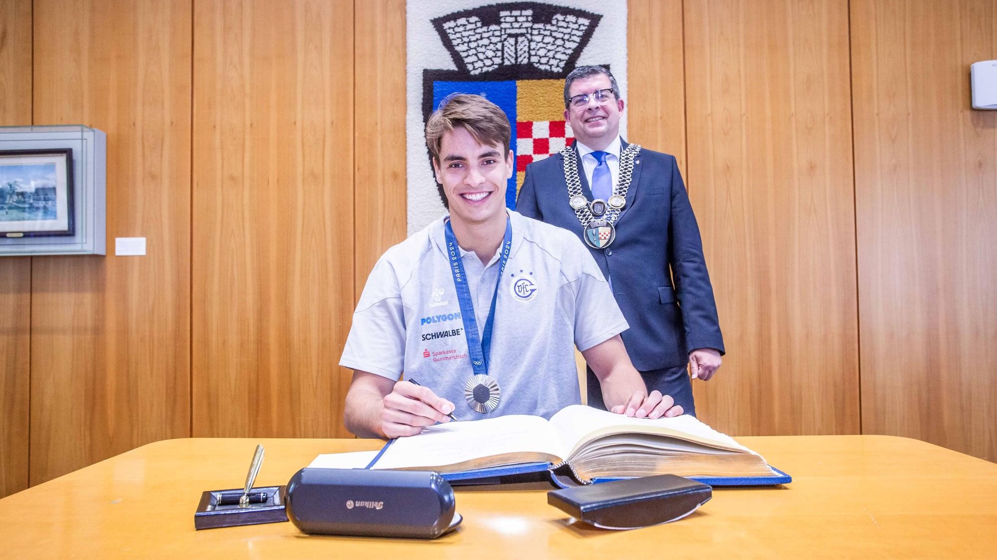 In Anwesenheit von Gummersbachs Bürgermeister Frank Helmenstein trägt sich Handballer Julian Köster ins Goldene Buch der Stadt ein.
