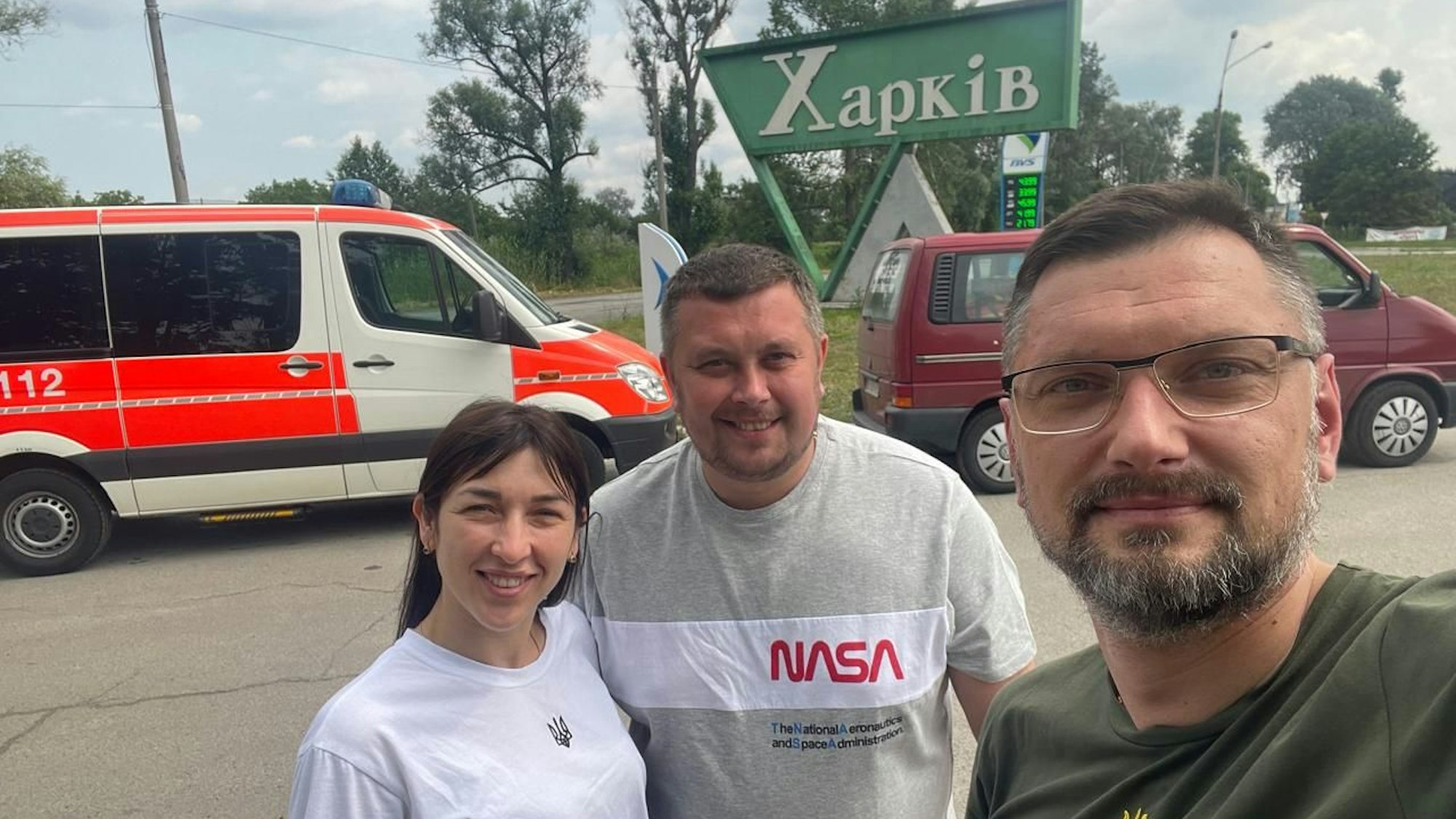 Ein Mann macht ein Selfie von sich und einem Krankenwagen im Hintergrund.