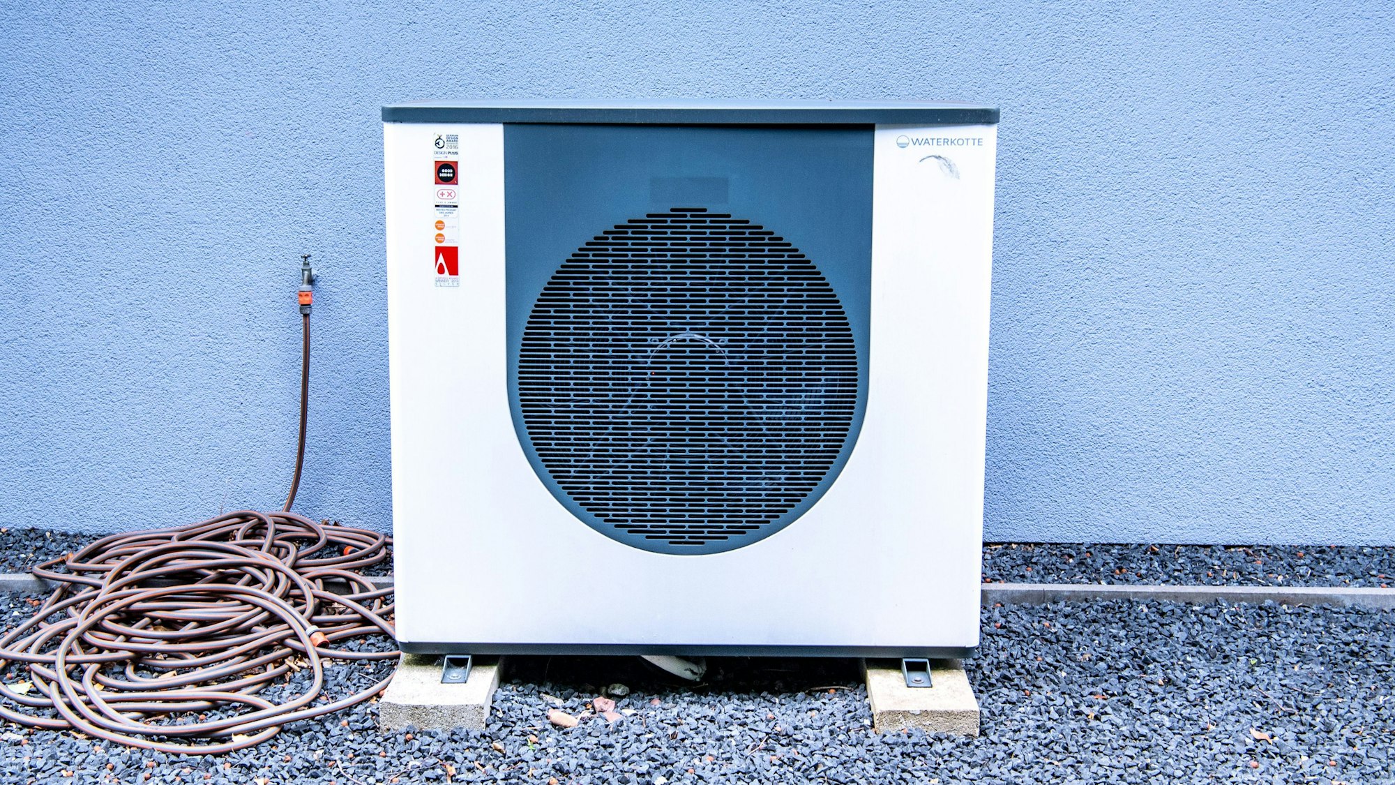 Die Lüftungsanlage einer Wärmepumpe vor einem Haus.