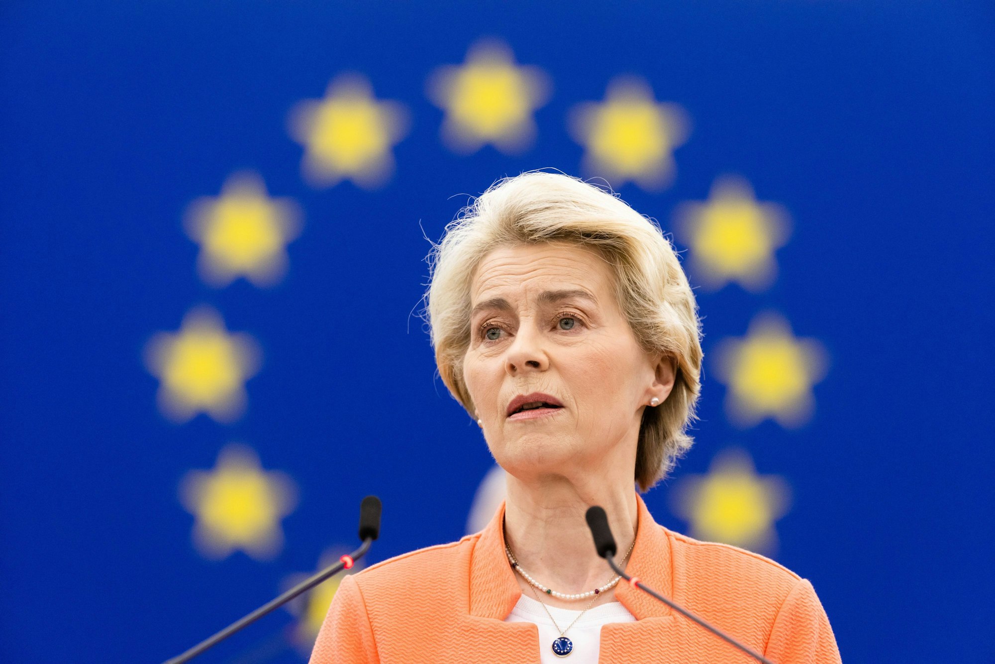 Ursula von der Leyen steht hinter zwei Mikrofonen.
