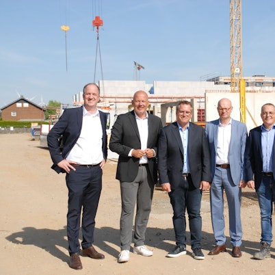 Männer stehen vor einer Baustelle.