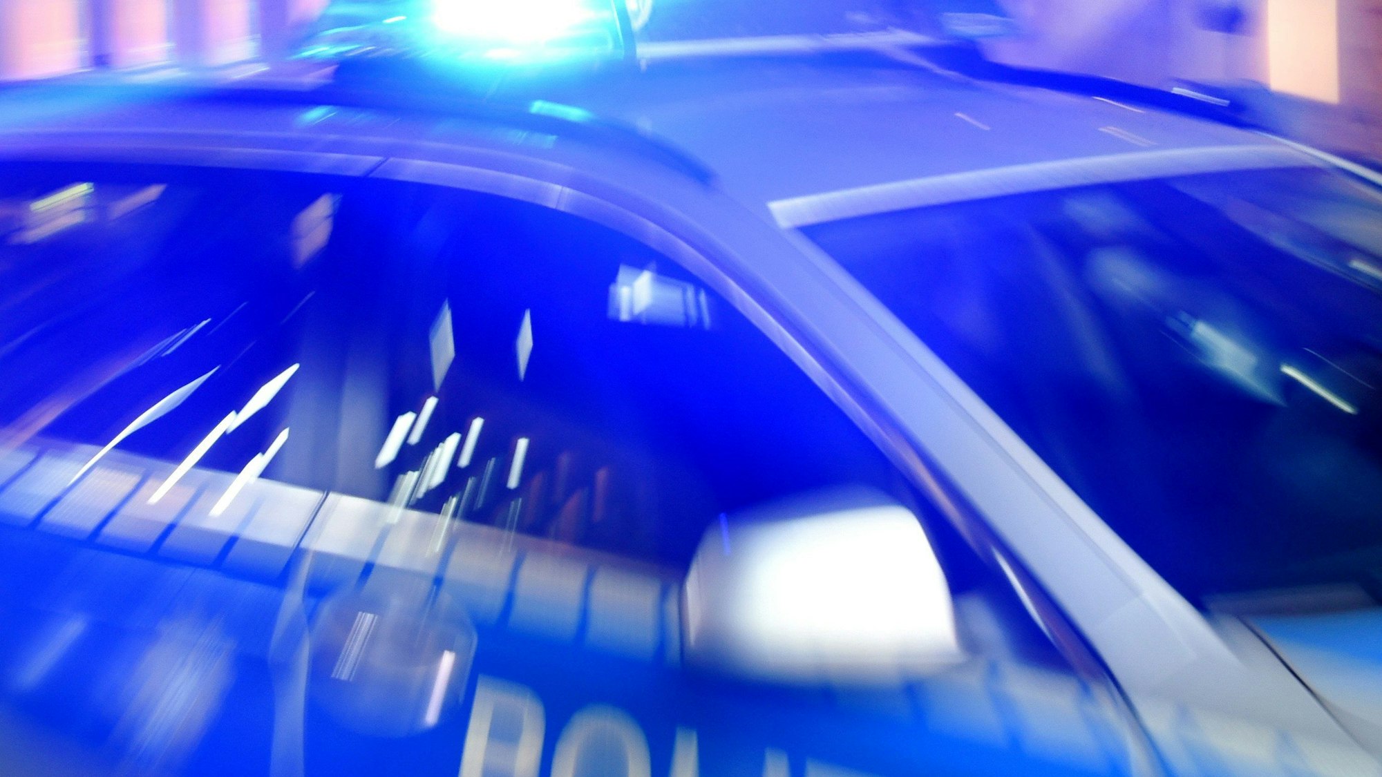 Ein Streifenwagen der Polizei steht mit eingeschaltetem Blaulicht auf der Straße.