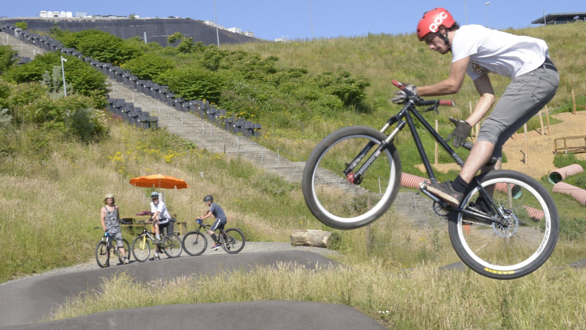 Ein Fahrradfahrer fliegt über eine Asphaltpiste.