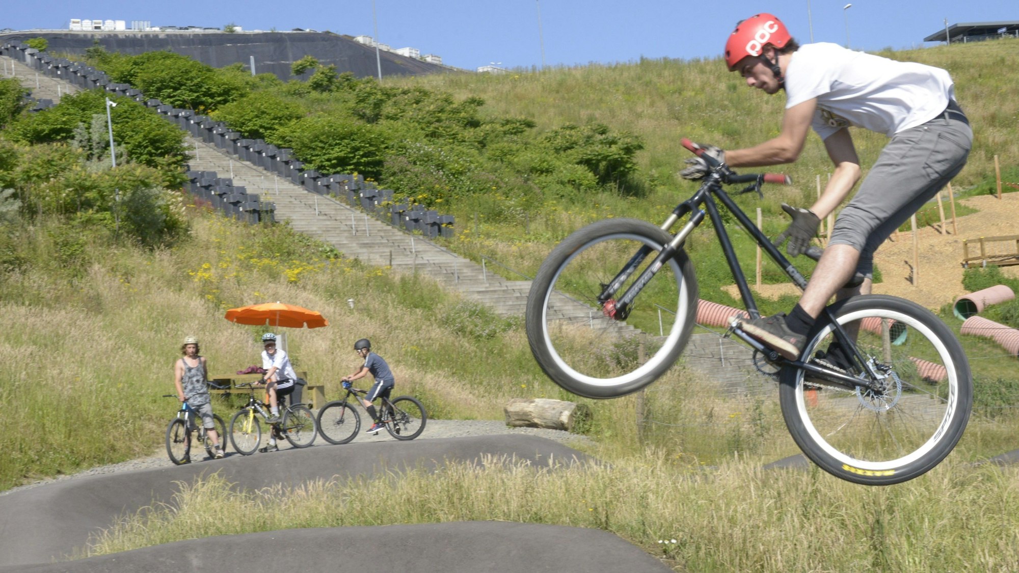 Ein Fahrradfahrer fliegt über eine Asphaltpiste.