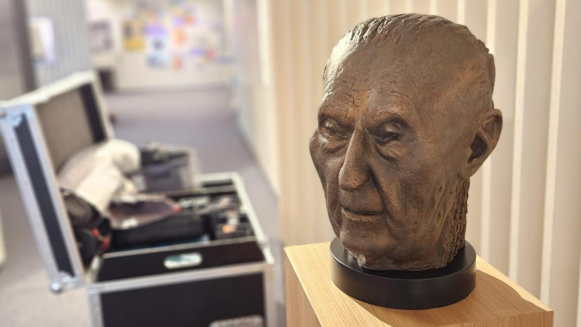 Eine Büste von Konrad-Adenauer auf einem Podest, daneben ein offener Werkzeugkoffer.