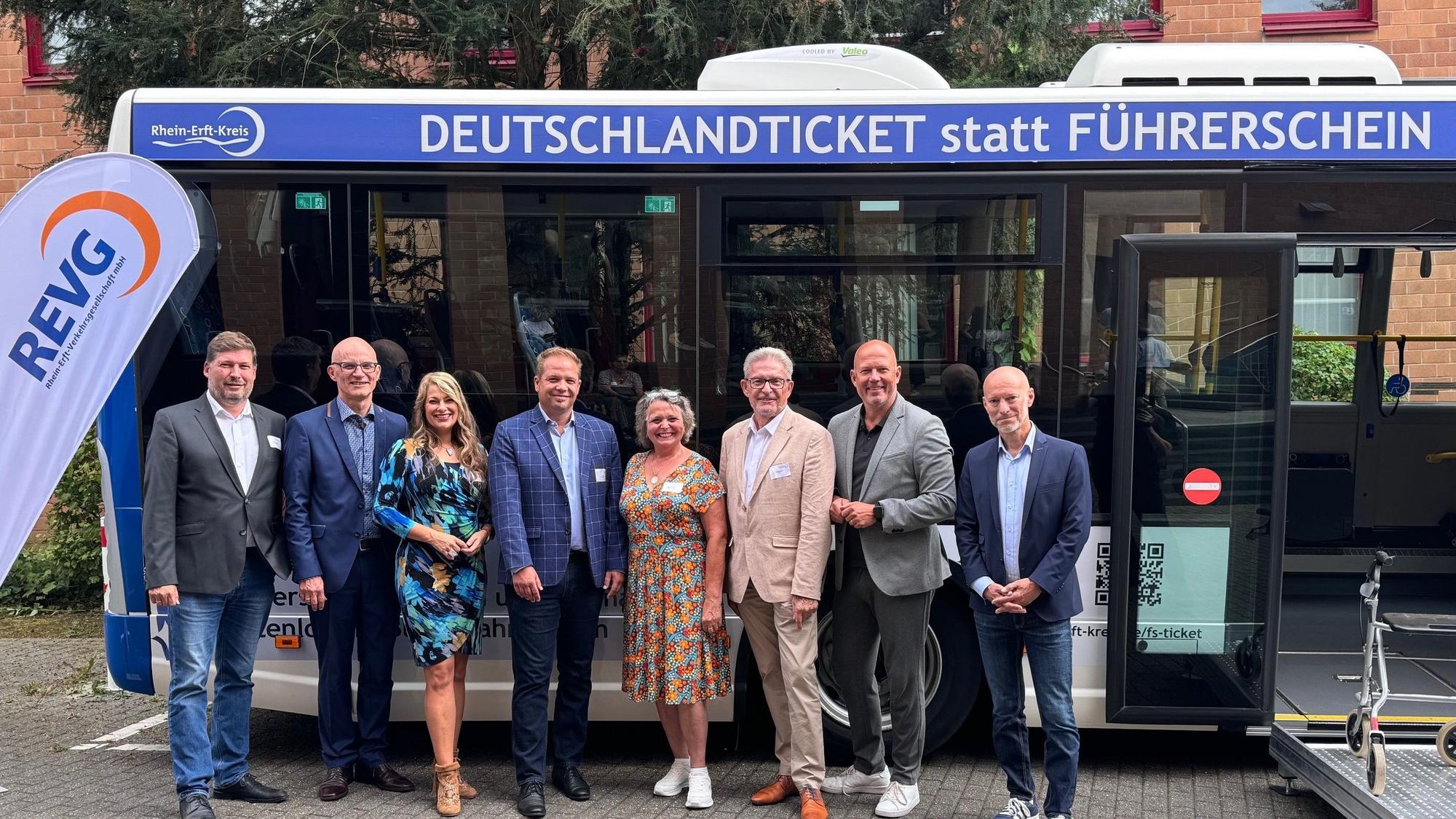 Das Foto zeigt eine Gruppe von Männern und Frauen vor einem Bus mit der Aufschrift „Deutschlandticket statt Führerschein“: