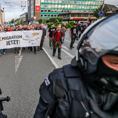 Solingen: Im Zuge einer Demonstration zeigen Teilnehmer aus dem rechten Lager am Montagabend (27. August) ein Plakat mit der Aufschrift „Remigration jetzt!“.