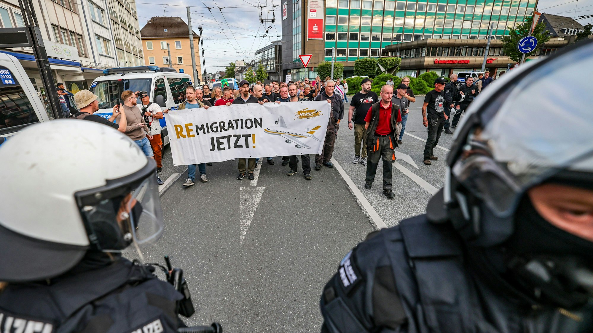 Solingen: Im Zuge einer Demonstration zeigen Teilnehmer aus dem rechten Lager am Montagabend (27. August) ein Plakat mit der Aufschrift „Remigration jetzt!“.