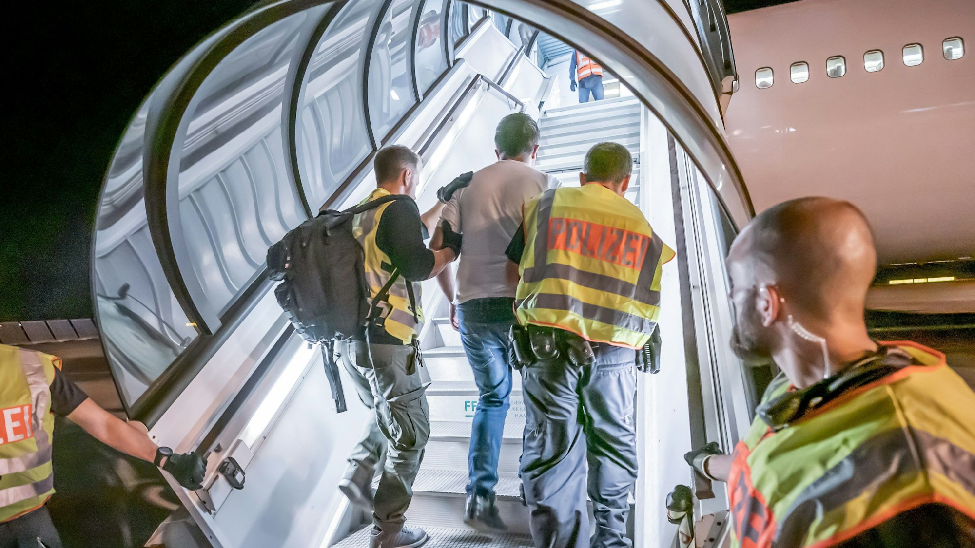 Polizeibeamte begleiten einen Afghanen auf dem Flughafen Leipzig-Halle in ein Charterflugzeug