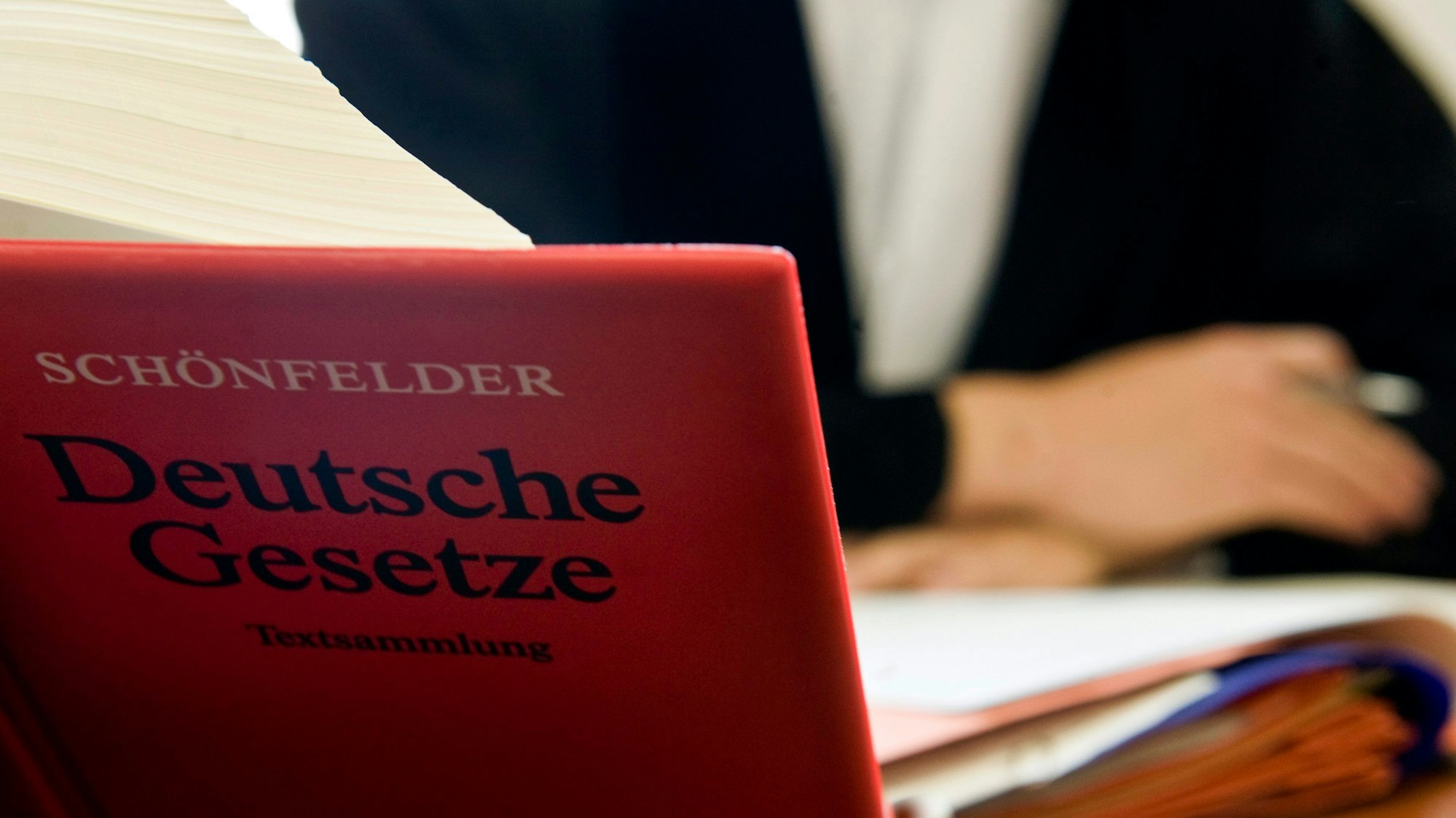Ein Anwalt sitzt hinter der aufgeschlagenen „Schönfelder Textsammlung Deutsche Gesetze“.
