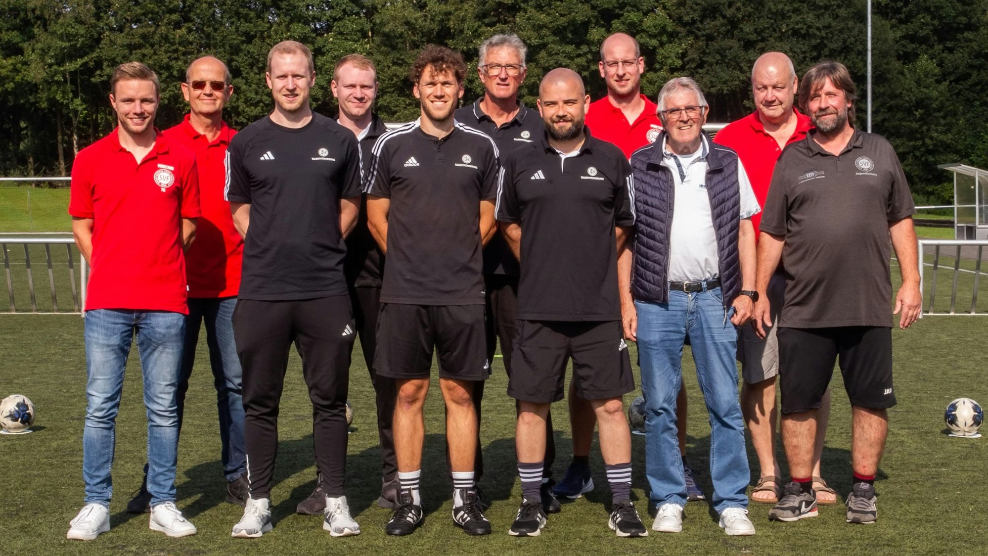 Zu sehen sind mehrere Männer, die sich auf einem Fußballplatz aufgestellt haben.