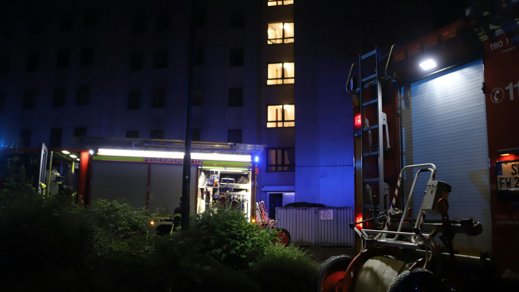 Feuerwehrautos stehen vor einem Mehrfamilienhaus.