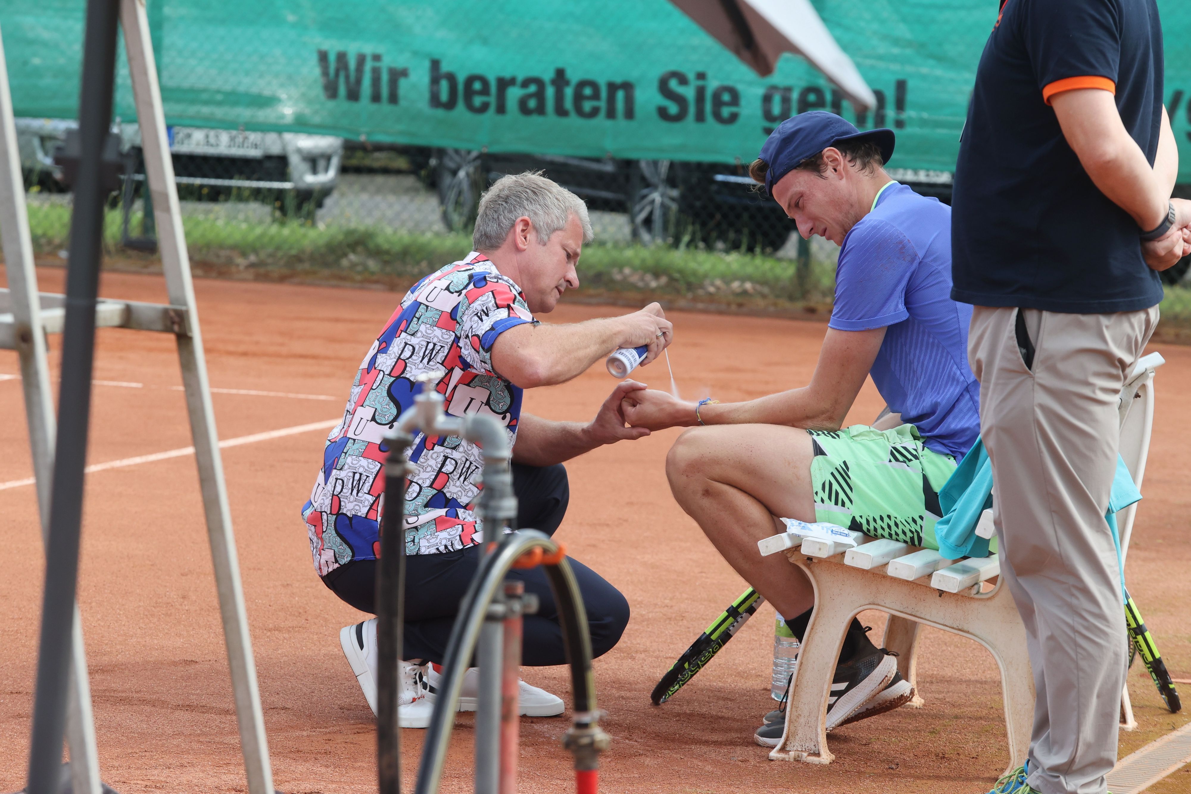 Tennisspieler Gabriel Décamps wird am Rande eines Turniers am Handgelenk behandelt.