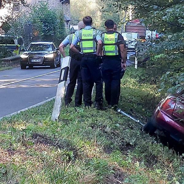 Der Wagen eines Verdächtigen liegt im Graben, Polizisten stehen daneben.