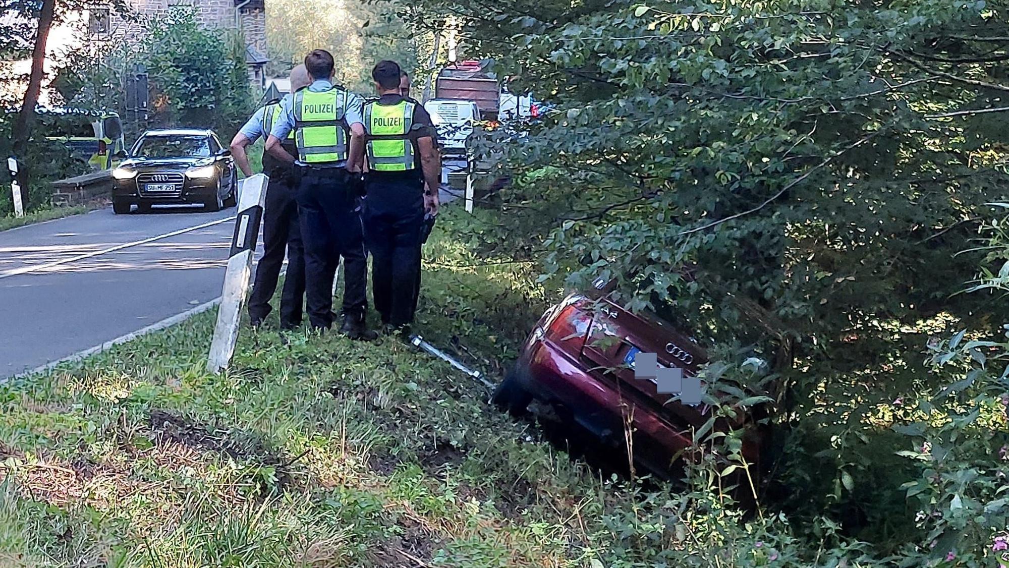 Der Wagen eines Verdächtigen liegt im Graben, Polizisten stehen daneben.