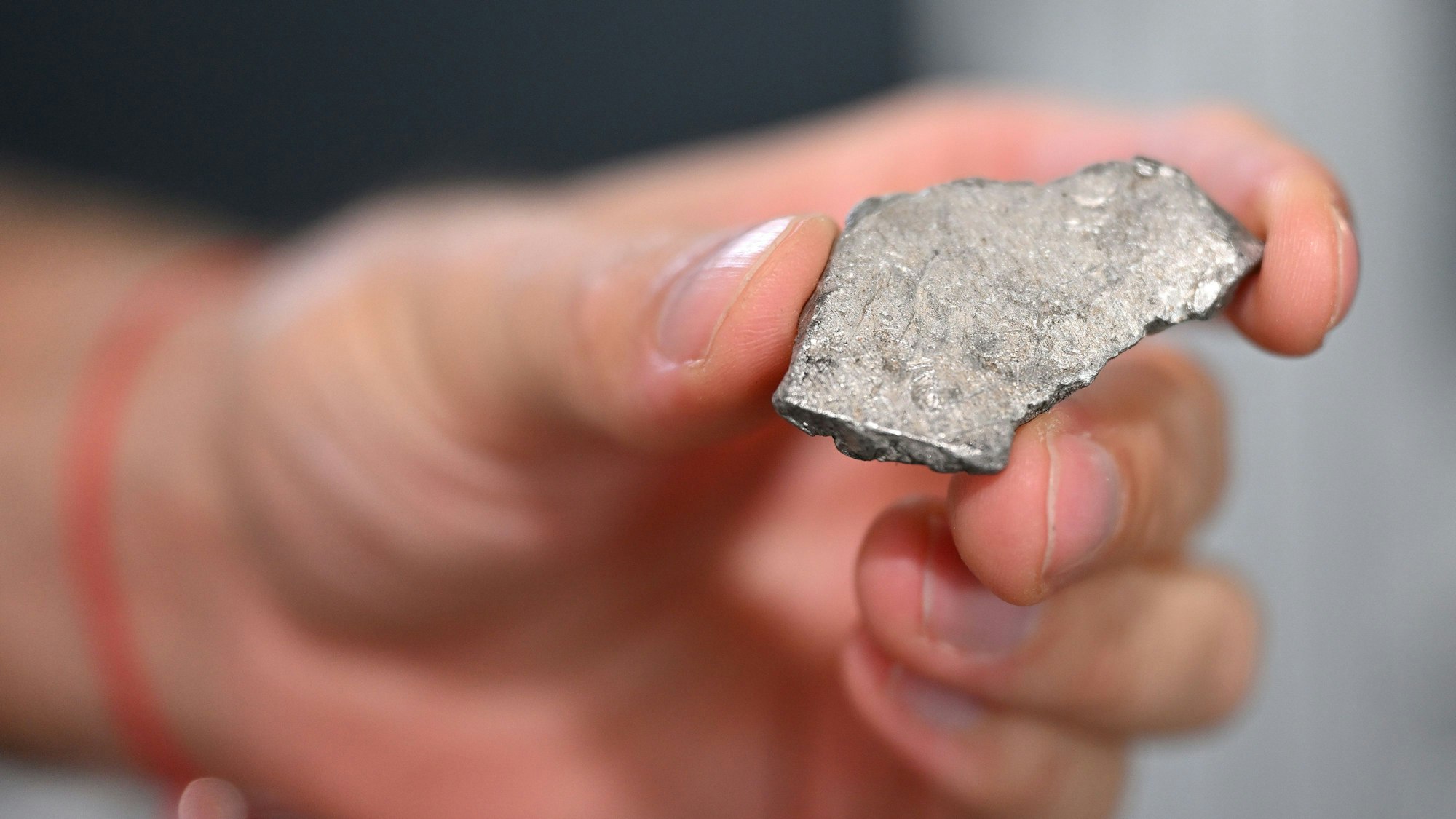 Eine Hand hält ein Stück Metallschrott.