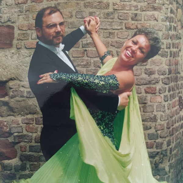 Die beiden tanzen gemeinsam. Jutta Zodet trägt ein grünes Kleid, Ralf Zodet trägt einen Frack und eine eckige Brille.