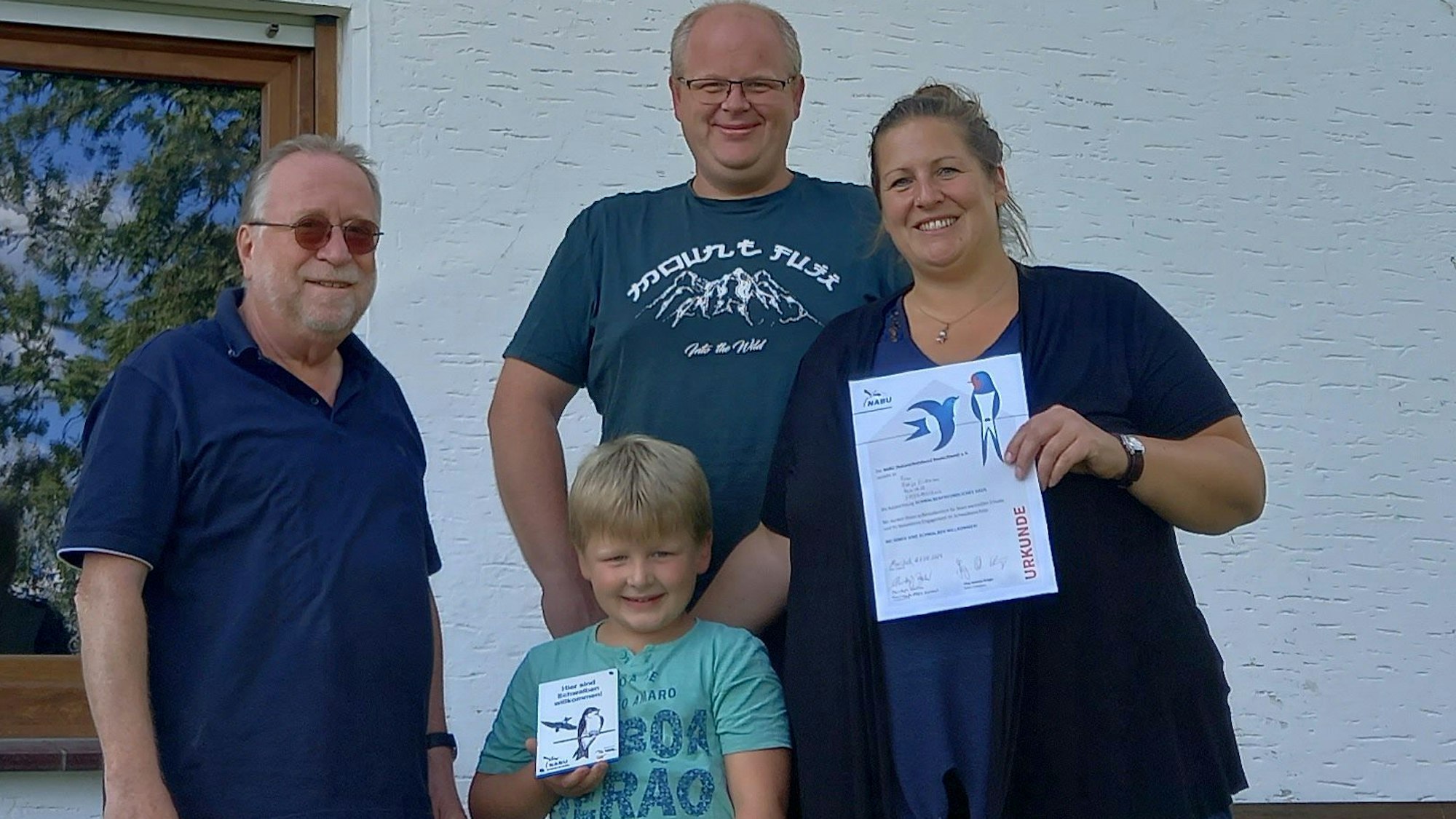 Christoph Buchen (links), Vorsitzender der Nabu-Ortsgruppe in der Gemeinde Morsbach, überreicht Katja Eichmann und Kevin Brast mit Sohn Ole Urkunde und Plakette für ihr schwalbenfreundliches Haus in der Ortschaft Wallerhausen.