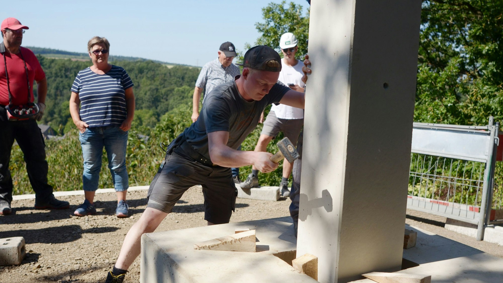 Jakob Gebertz arbeitet mit einem Hammer, während Kollegen und andere Beobachter zuschauen.