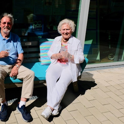 Ein Senior und eine Seniorin auf der Plauderbank vor dem Raum an der Palanterstraße 13.