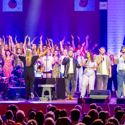 Ein Chor singt auf einer Bühne.