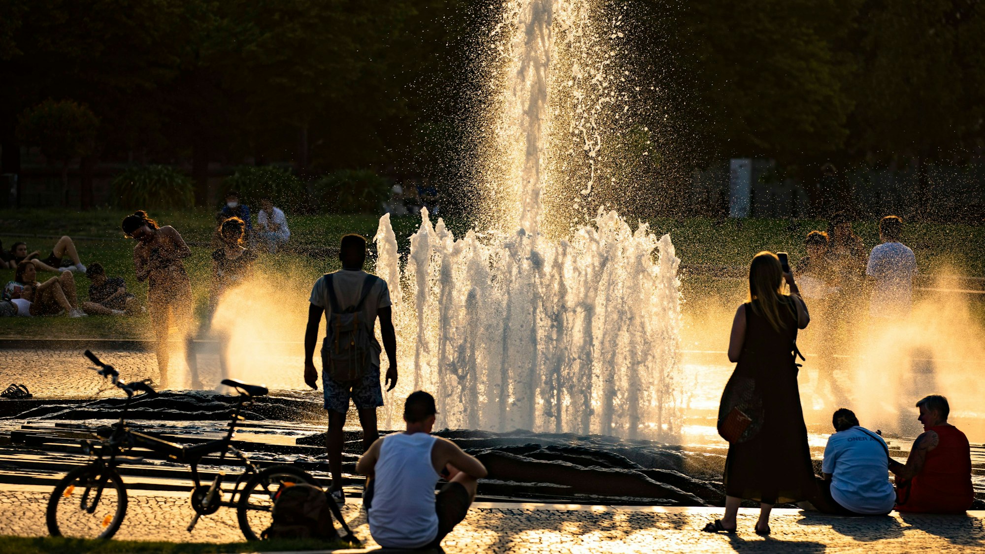 Menschen bei dem Brunnen im Lustgarten auf der Museumsinsel in Berlin am 20. Juli 2022.