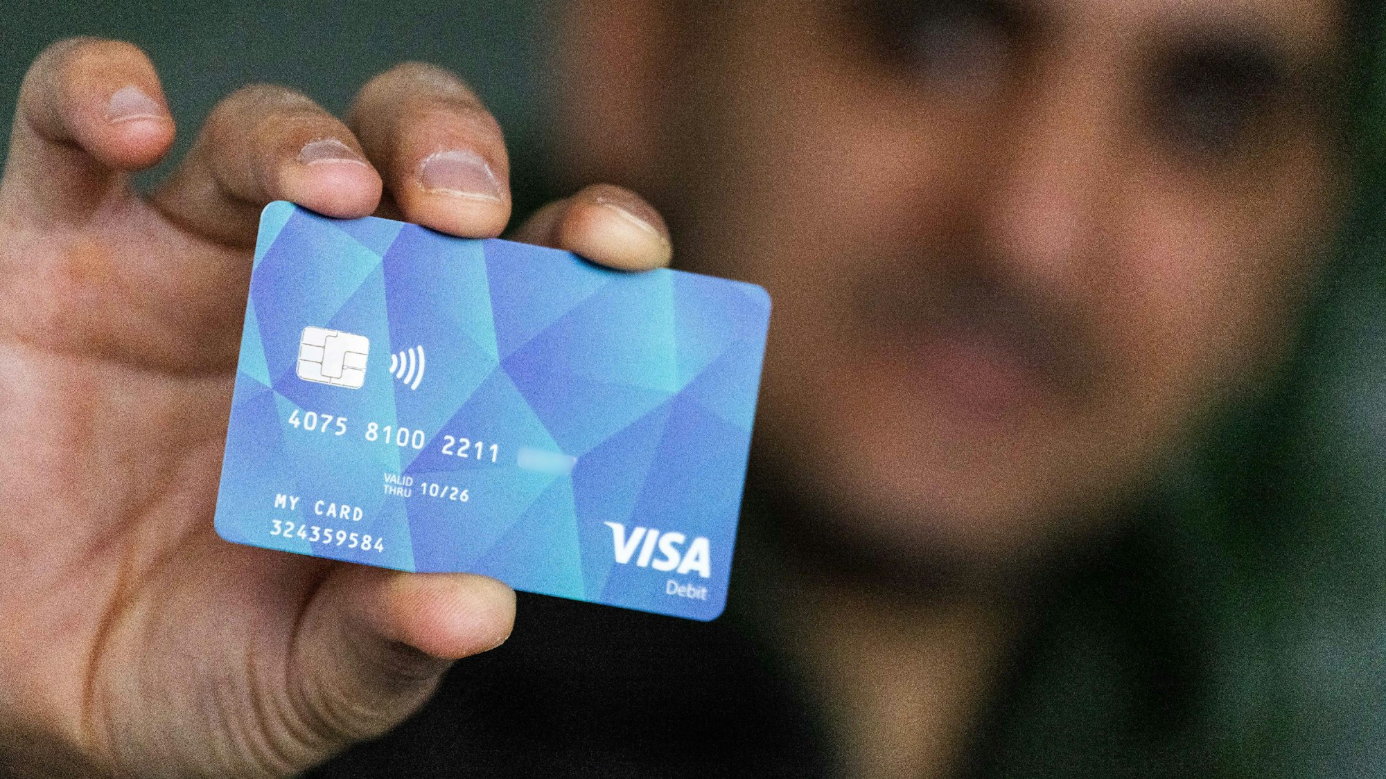 Ein Geflüchteter hält eine Debitcard in der Hand.