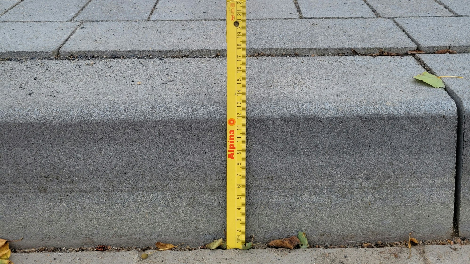 Ein Bordstein, davor ein Zollstock.