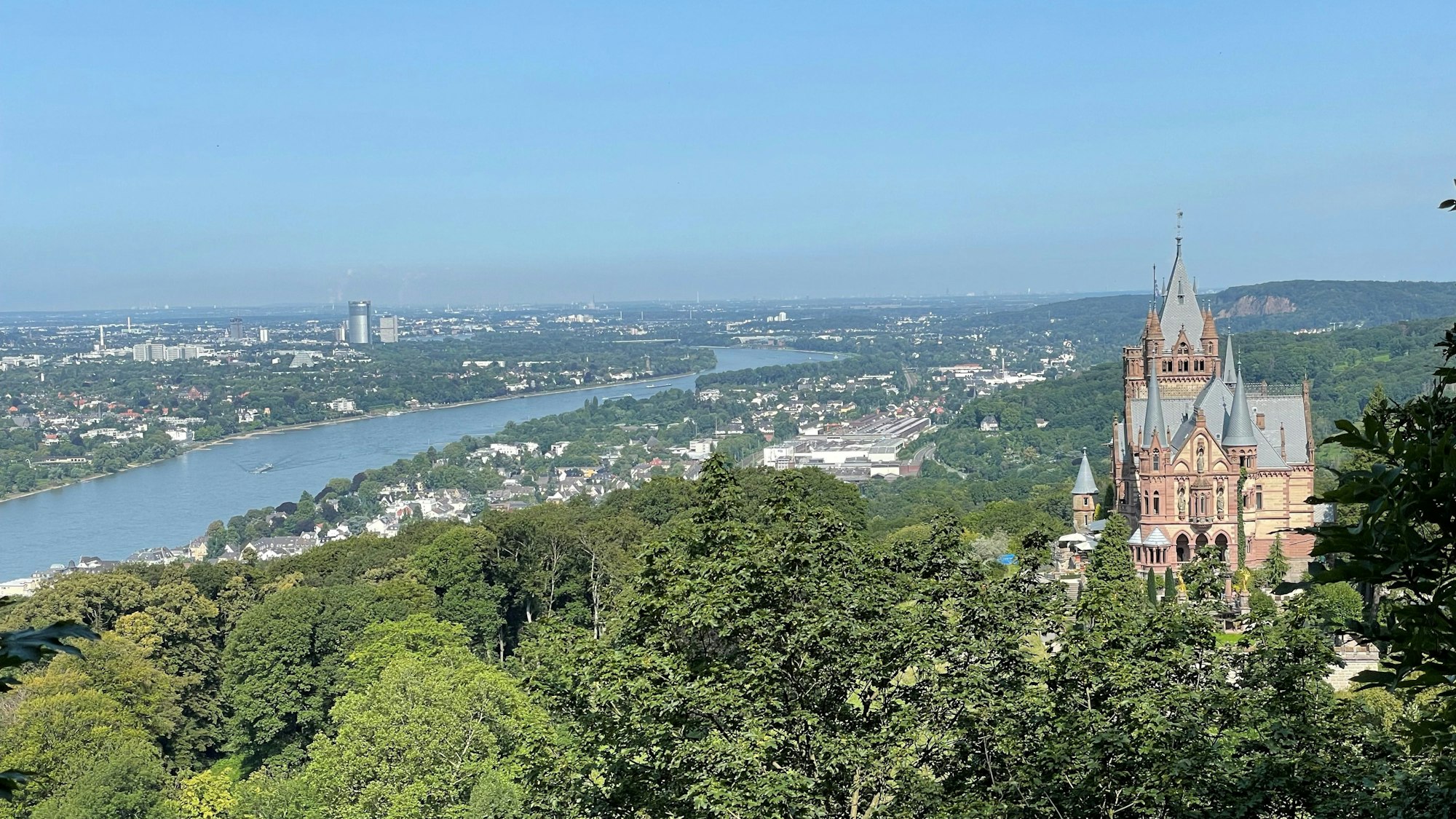 Vorne ist die Drachenburg und im Hintergrund Bonn und der Rhein zu sehen.