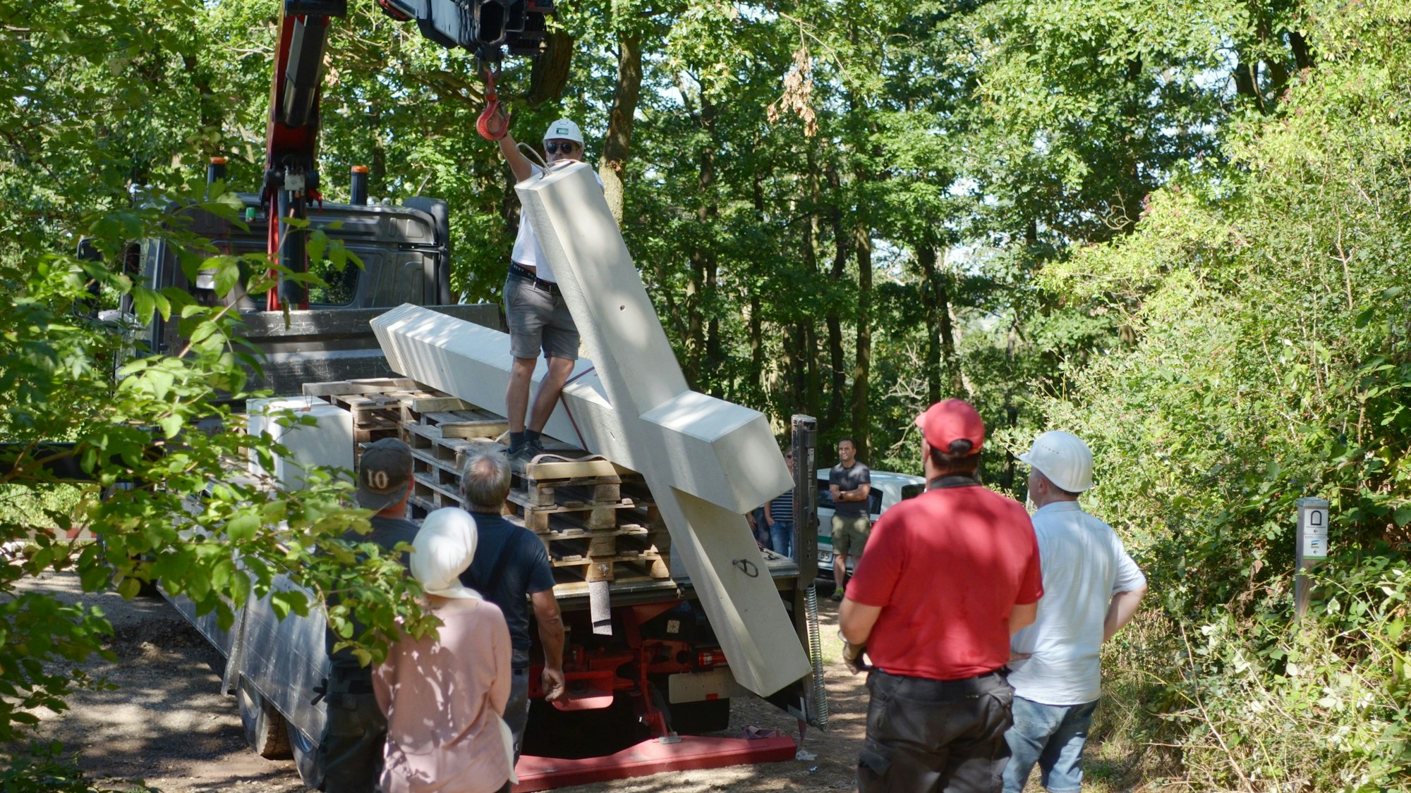 Mitarbeiter der Baufirma befestigen das Kreuz am Ausleger eines Ladekrans.