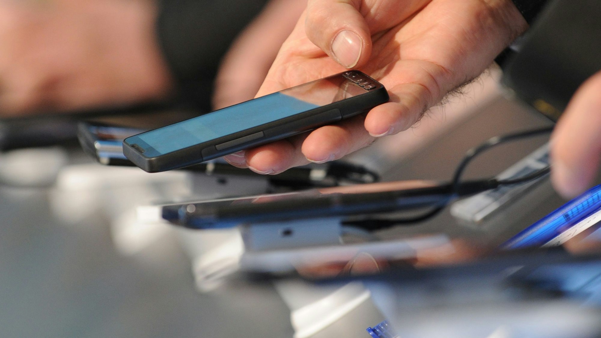 Hände halten Handys in der Hand.