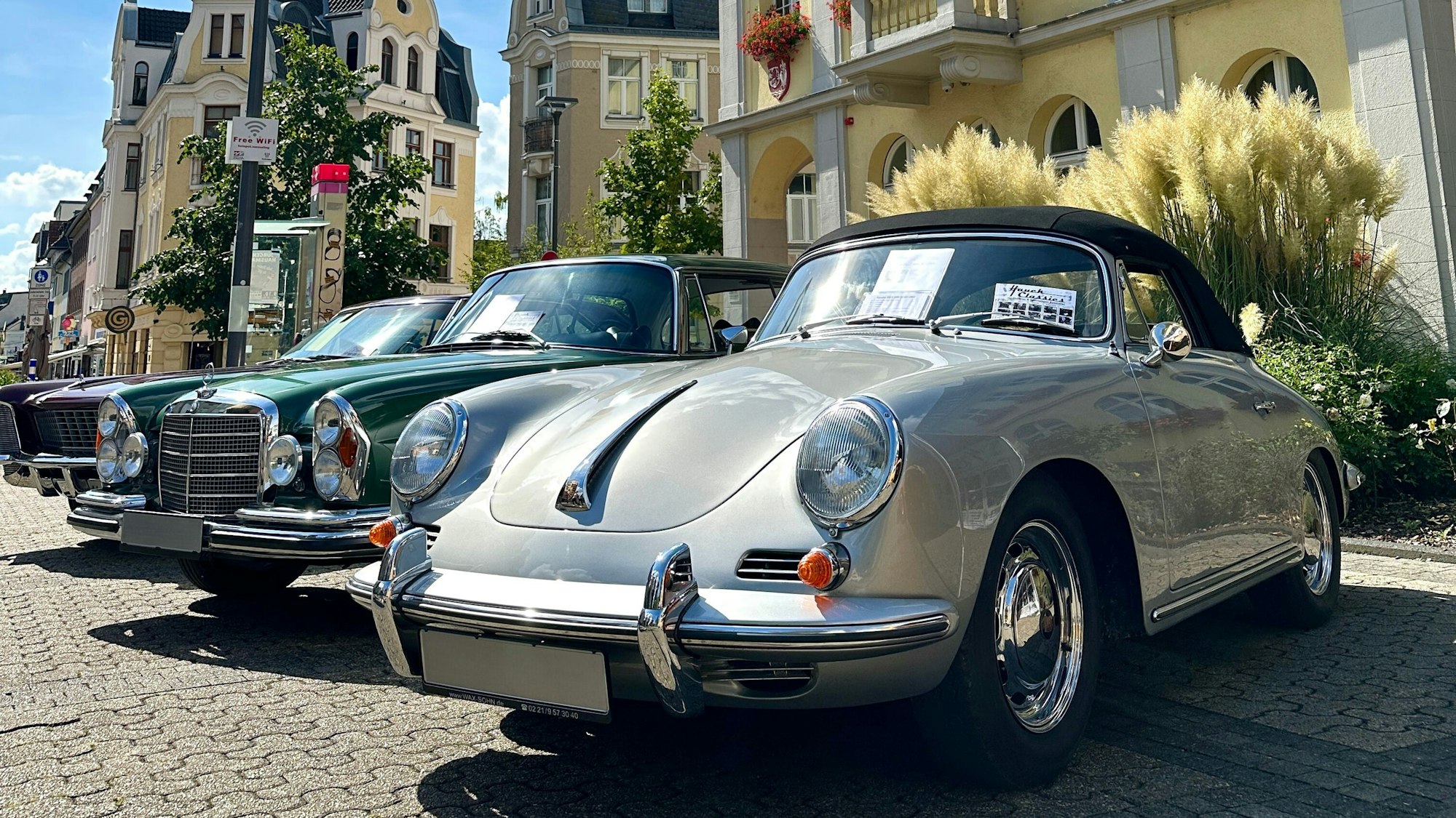 Auf dem Bild sind ein grüner und ein grauer Oldtimer zu sehen.