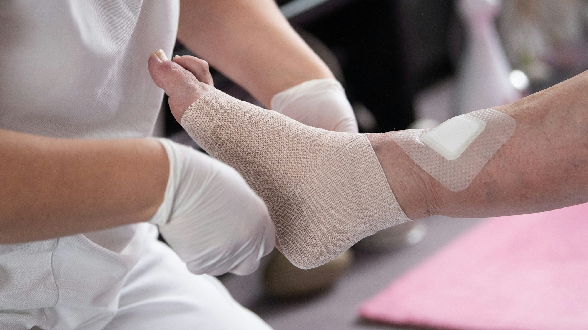 Eine Pflegefachkraft legt einen Kompressionsverband an.