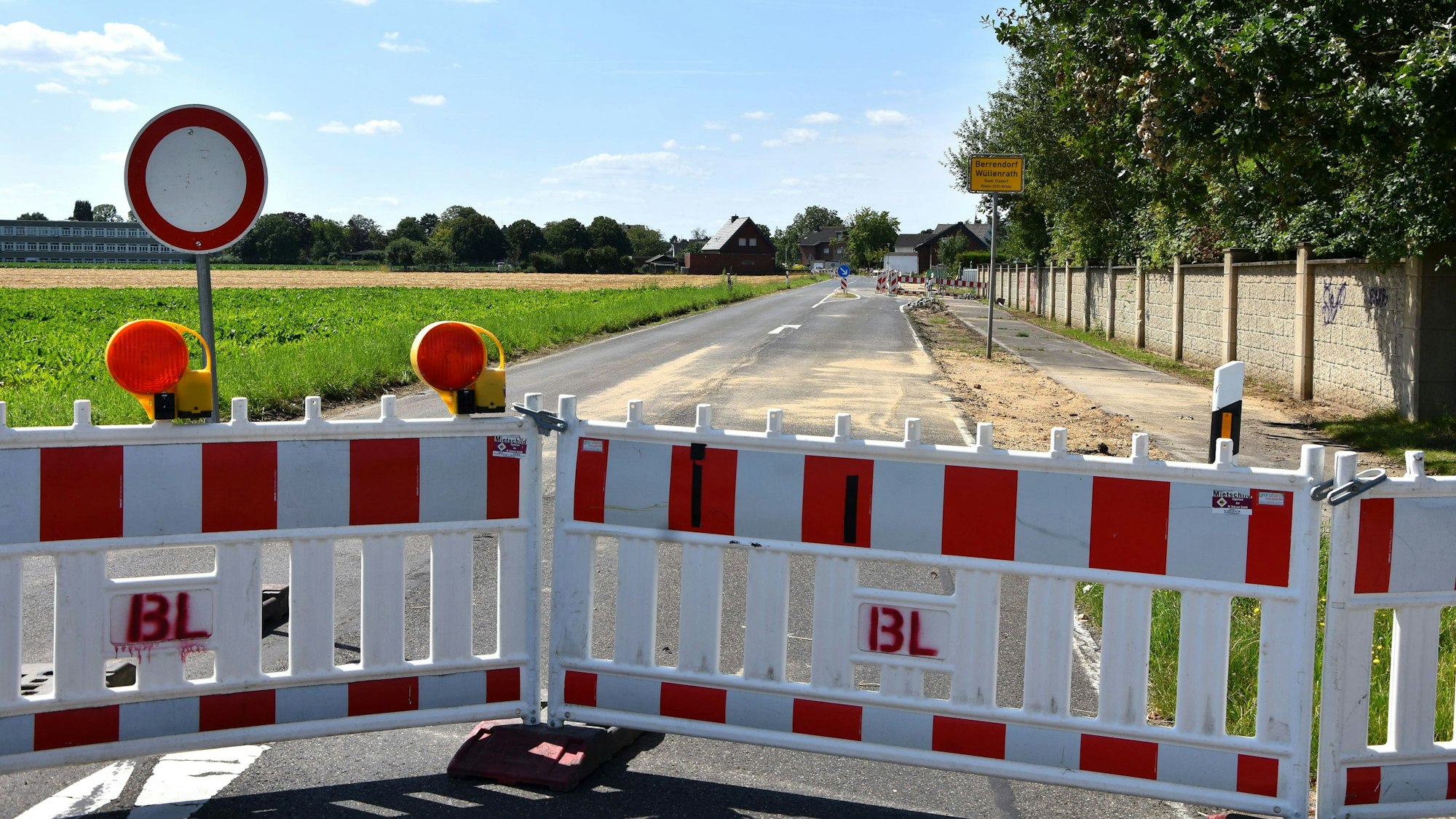 Zu sehen ist ein Absperrzaun an einer Straße.