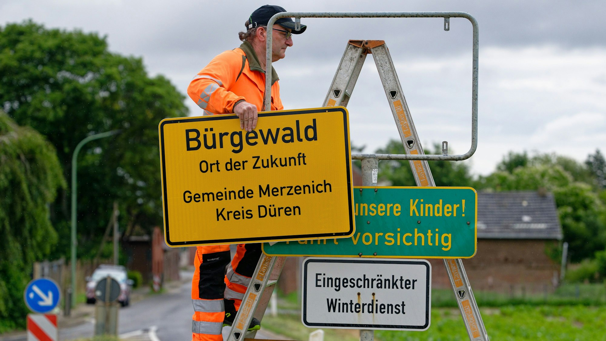 Mitarbeiter von Straßen NRW, bringt ein neues Ortsschild Namen am Ortseingang des Braunkohledorfes Morschenich an.