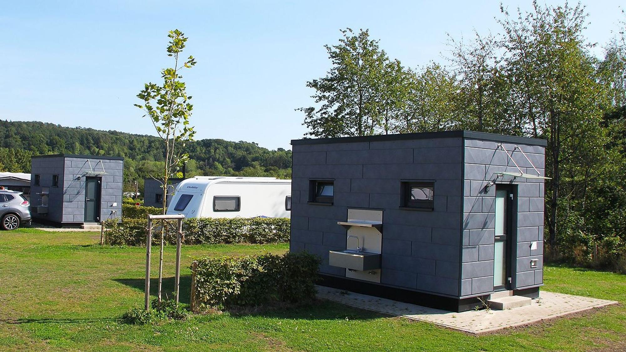 Das Foto zeigt mehrere WC- und Küchenhäuschen, die im Eifel Camp verteilt sind.