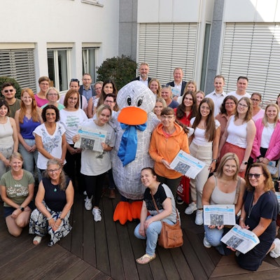 Das Maskottchen Paula Print steht in einer Gruppe von Menschen.