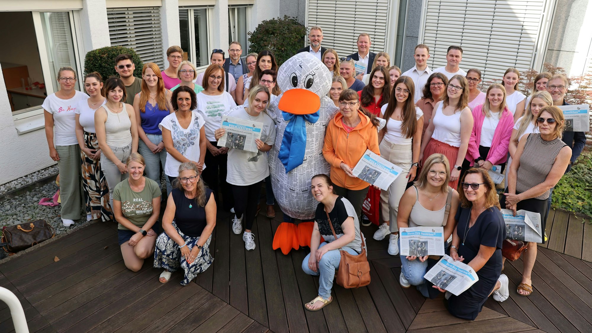 Das Maskottchen Paula Print steht in einer Gruppe von Menschen.