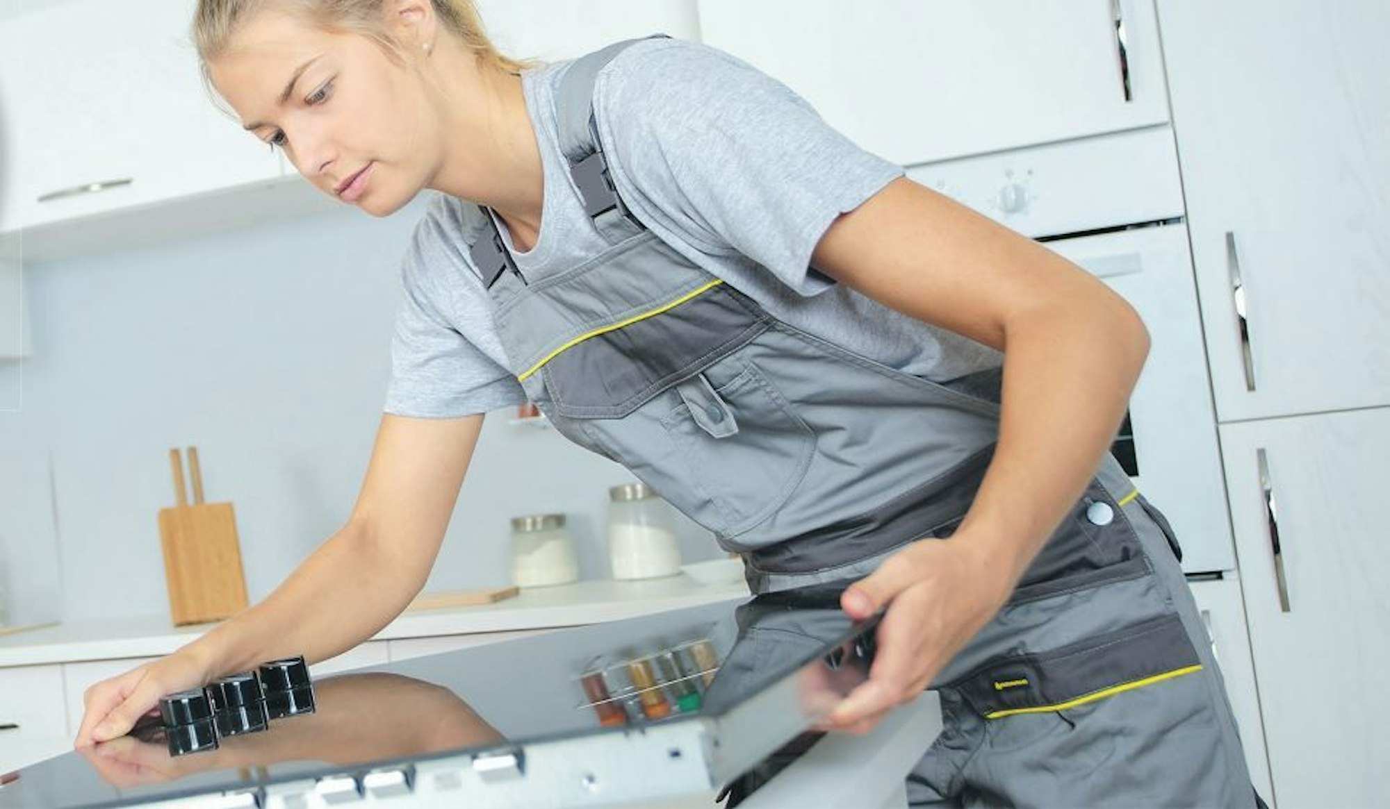 Handwerkerin beim Einbau eines Herdes.