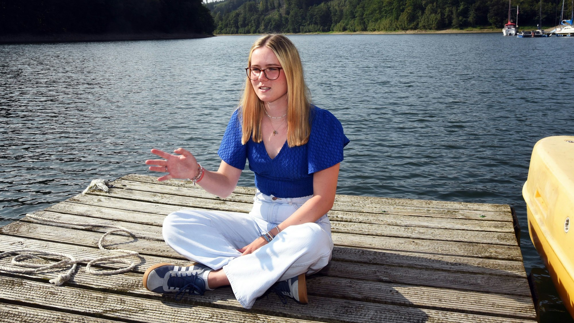 Eine junge Frau sitzt auf einem Bootssteg an der Aggertalsperre.
