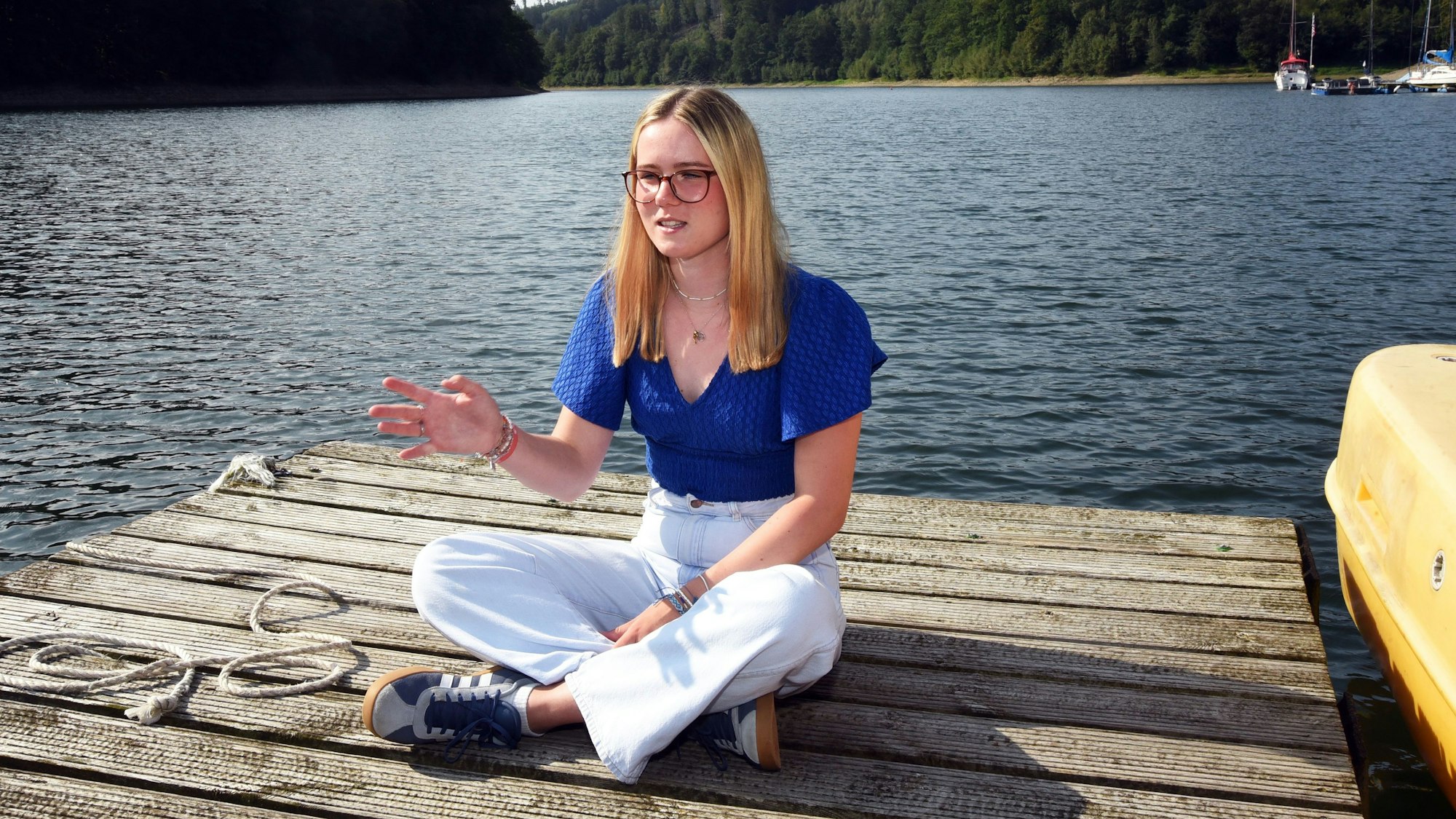 Eine junge Frau sitzt auf einem Bootssteg an der Aggertalsperre.